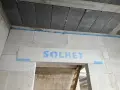 Piana montażowa tworzy dylatację między betonowymi stropami a ścianą z bloczków gazobetonowych. Na nadprożu widoczny napis "SOLBET".