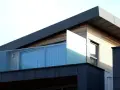 Nowoczesny budynek z drewnianą elewacją i szklanymi balustradami. Solidna hydroizolacja dachu zapewnia ochronę przed wilgociącią.
