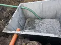 Szambo betonowe 10m3 cena z montażem. Instalacja wkopana w ziemię, widoczne rury doprowadzające.