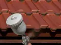 Malowanie betonu na dachu za pomocą pistoletu natryskowego. Czerwona dachówka zyskuje nową warstwę ochronną.