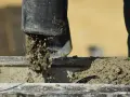 Beton wylewany z rury, rozpoczyna się proces jego wiązania. Czas, ile schnie beton, zależy od wielu czynników.
