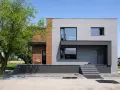 Nowoczesny dom z betonowych bloczków i drewna, nawiązujący stylem do **elewacji domów z lat 70-tych**, ale z odświeżonym, minimalistycznym charakterem.