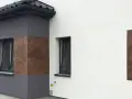 Nowoczesna elewacja z elementami imitującymi drewno, wykonana z tynków cementowo wapiennych.