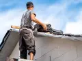 Pracownik układa dachówki na dachu dwuspadowym. Szacowany koszt dachu dwuspadowego 200m2.