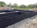 Fundament gotowy do izolacji. Czarna membrana z wypustkami, czyli izoplast b, chroni ściany przed wilgocią.