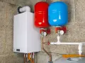 Nowoczesny kocioł gazowy z dwoma zbiornikami przeponowymi (czerwonym i niebieskim) oraz instalacją hydrauliczną.