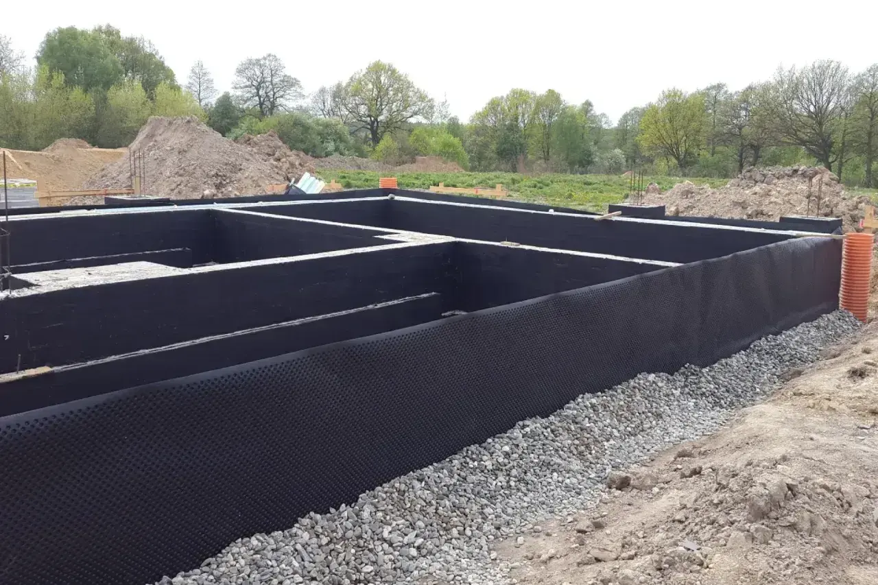 Fundament gotowy do izolacji. Czarna membrana z wypustkami, czyli izoplast b, chroni ściany przed wilgocią.