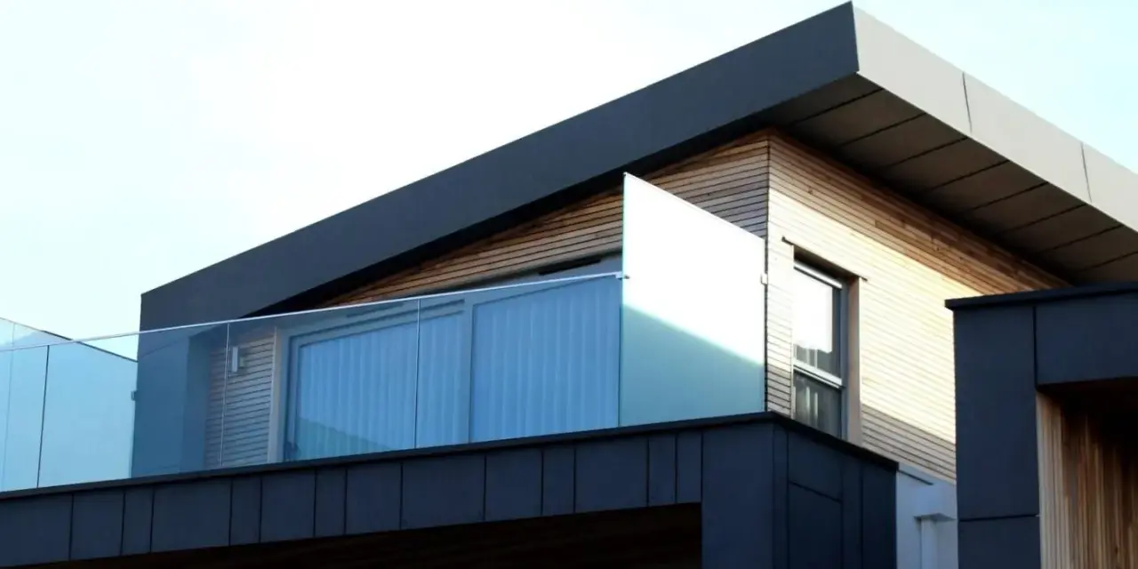 Nowoczesny budynek z drewnianą elewacją i szklanymi balustradami. Solidna hydroizolacja dachu zapewnia ochronę przed wilgociącią.