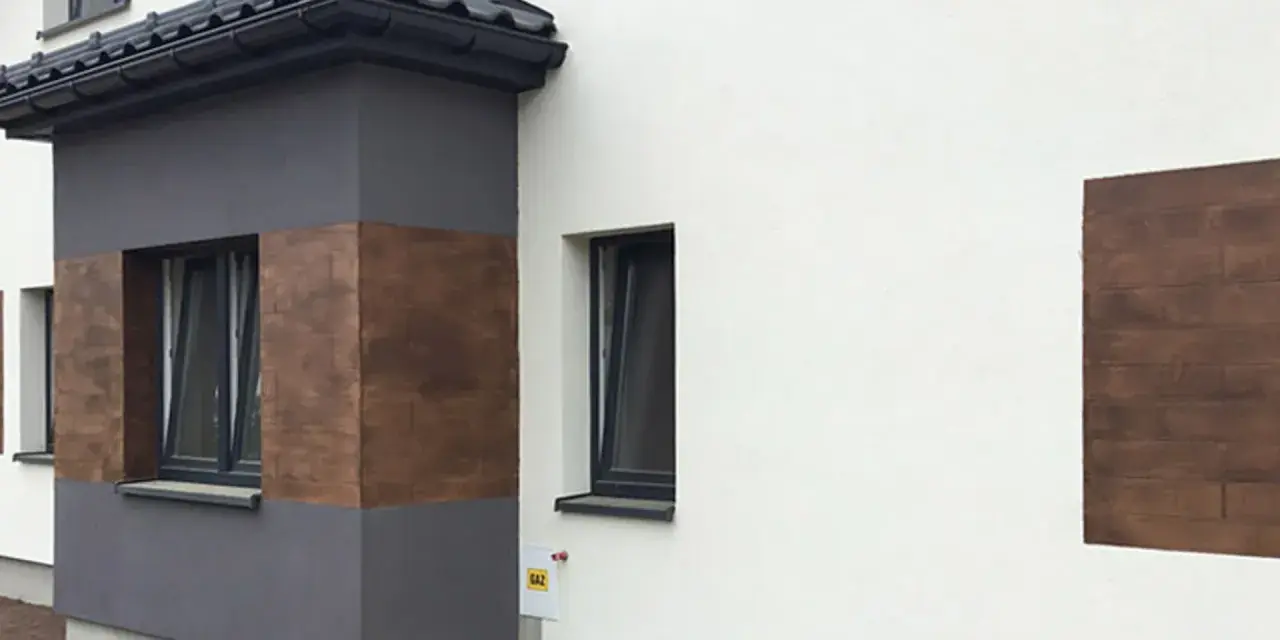 Nowoczesna elewacja z elementami imitującymi drewno, wykonana z tynków cementowo wapiennych.