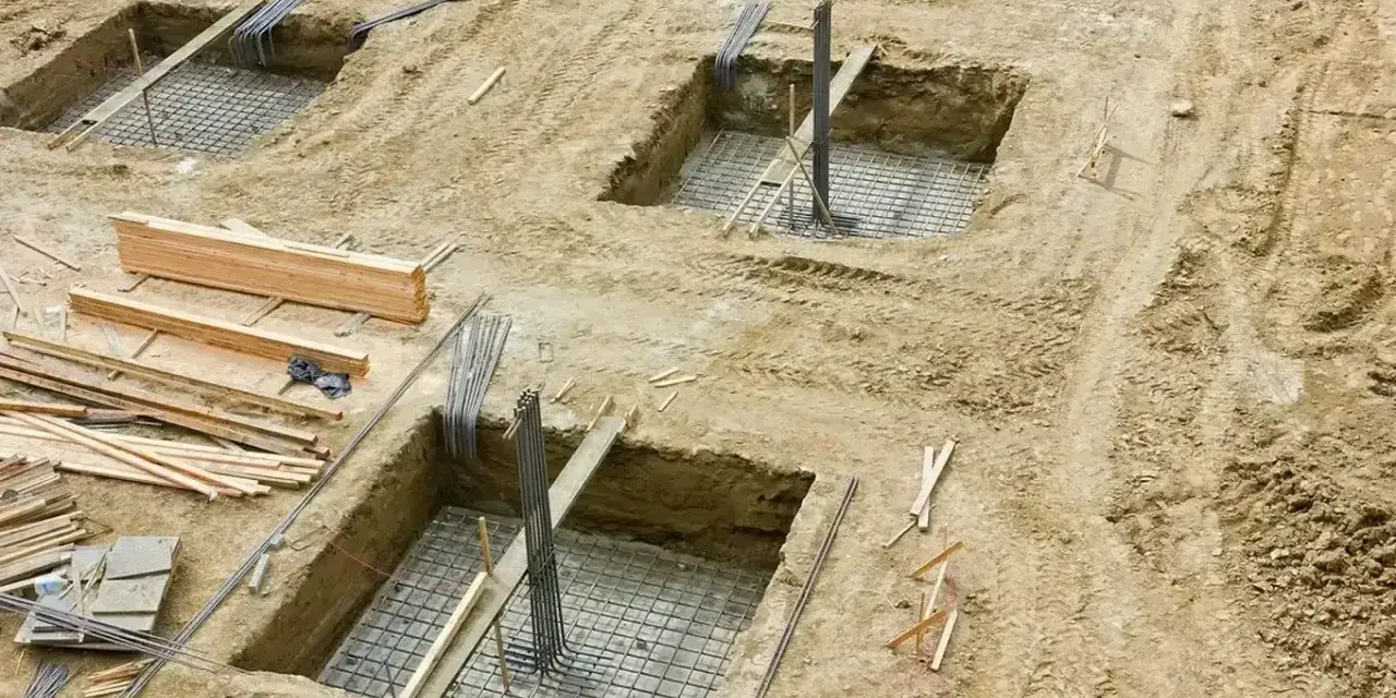 Wykopy pod fundamenty, zbrojenie i drewno budowlane. Trwa podbijanie fundamentów pod przyszły budynek.