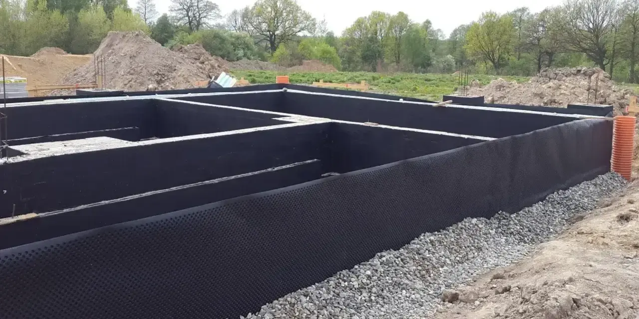 Fundament gotowy do izolacji. Czarna membrana z wypustkami, czyli izoplast b, chroni ściany przed wilgocią.