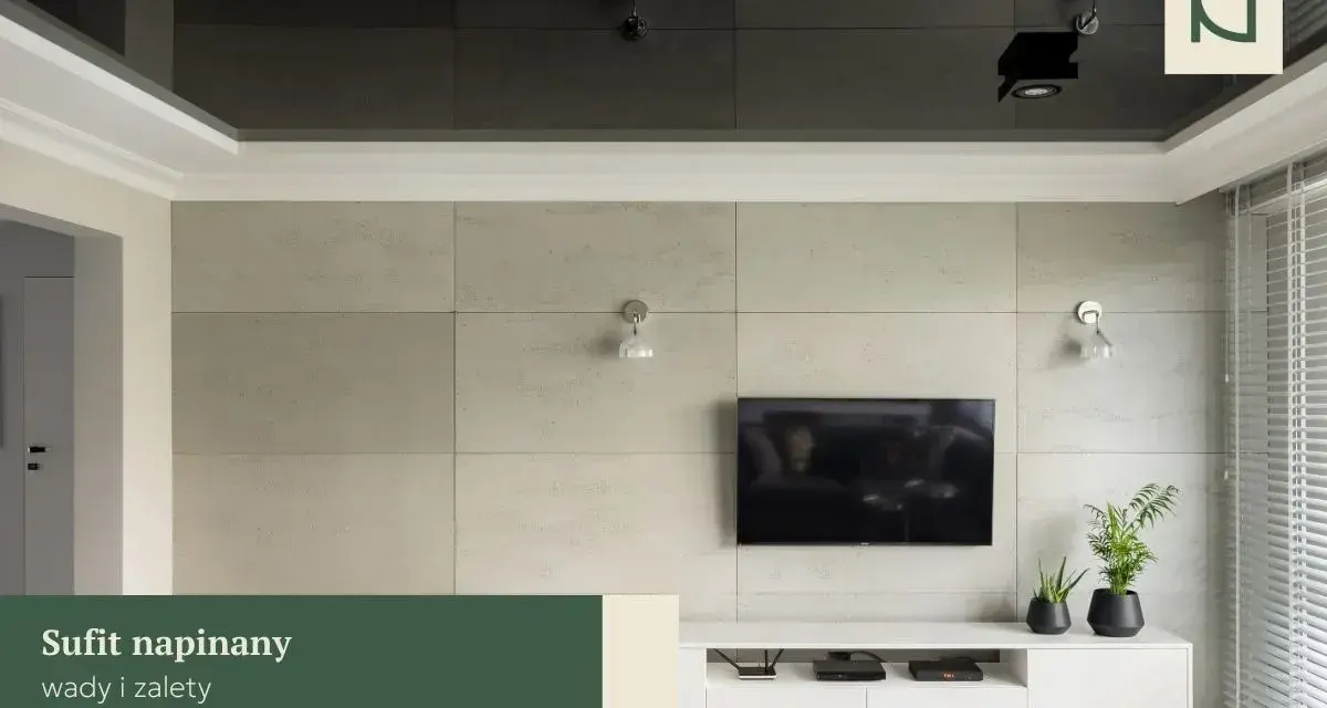 Nowoczesny salon z telewizorem na tle betonowej ściany. Lustrzany sufit napinany dodaje głębi, a subtelna **faseta** podkreśla elegancję wnętrza.