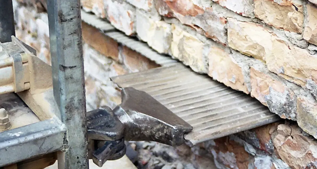 Prace przy izolacji fundamentów w starym domu. Widać fragment maszyny i ceglaną ścianę.