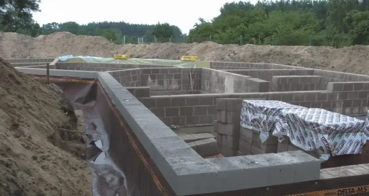 Fundament domu z bloczków betonowych, z widoczną izolacją i przygotowaniem pod keramzytobeton. Budowa w toku.