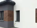 Nowoczesna elewacja z elementami imitującymi drewno, wykonana z tynków cementowo wapiennych.