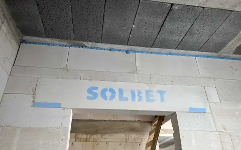 Piana montażowa tworzy dylatację między betonowymi stropami a ścianą z bloczków gazobetonowych. Na nadprożu widoczny napis "SOLBET".