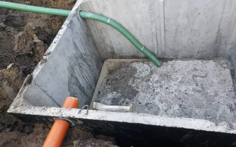 Szambo betonowe 10m3 cena z montażem. Instalacja wkopana w ziemię, widoczne rury doprowadzające.