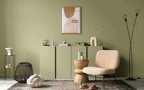 Przytulny salon w odcieniu **kolor sage**. Miękkie fotele, dekoracje i sztuka tworzą relaksującą atmosferę.