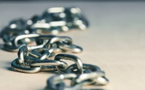 Metalowe szekle tworzą łańcuch, który może symbolizować siłę lub ograniczenia.