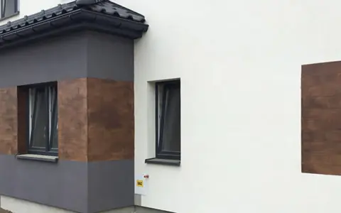 Nowoczesna elewacja z elementami imitującymi drewno, wykonana z tynków cementowo wapiennych.