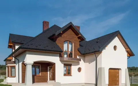 Nowoczesny dom z drewnianymi elementami i białym cokołem, zadaszonym wejściem i garażem.