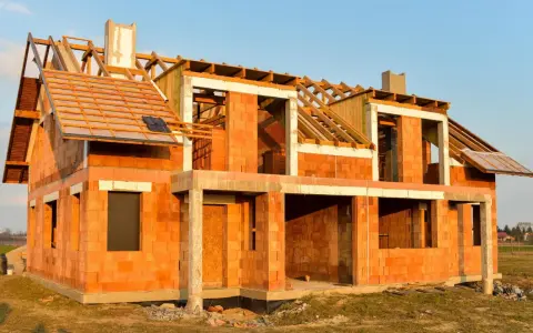 Budowa domu energooszczędnego z cegły ceramicznej. Widoczny szkielet dachu i otwory okienne.