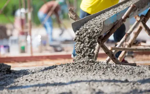 Beton wylewany z betoniarki. Pracownicy na budowie, zastanawiają się, ile cementu na kubik betonu potrzeba do wykonania solidnej konstrukcji.
