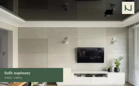 Nowoczesny salon z telewizorem na tle betonowej ściany. Lustrzany sufit napinany dodaje głębi, a subtelna **faseta** podkreśla elegancję wnętrza.