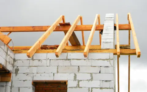 Drewniana więźba dachowa na budowie domu z bloczków betonowych. Sprawdź, jaka jest aktualna więźba dachowa cena.