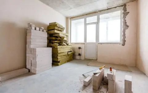 Materiały budowlane, w tym pustaki i wełna mineralna, czekają na **ocieplenie ścian od wewnątrz**.