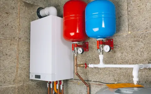 Nowoczesny kocioł gazowy z dwoma zbiornikami przeponowymi (czerwonym i niebieskim) oraz instalacją hydrauliczną.