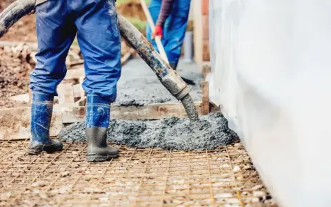Pracownicy wylewają beton na zbrojenie. Sprawdzamy, jaka jest suchy beton cena 1m3, by zaplanować budowę.