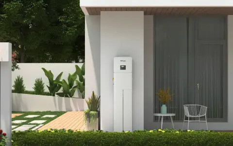 Biały magazyn energii 5 kW, stojący przy nowoczesnym domu, z zielenią i tarasem. Zastanawiasz się, na ile wystarczy taki magazyn energii?