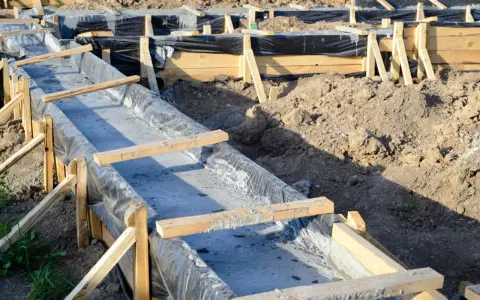 Budowa fundamentów: betonowe ławy w drewnianym szalunku, wyłożone czarną folią.