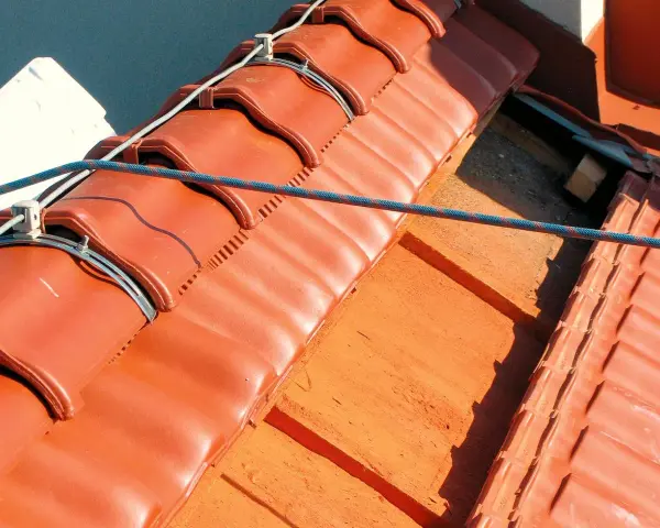 System piorunochronu na dachu z czerwonej dachówki, zabezpieczający przed uderzeniami pioruna.