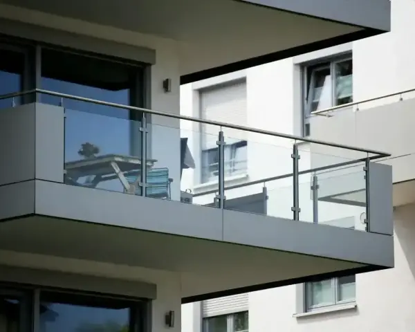Nowoczesna loggia z przeszklonymi balustradami, na której stoi stolik z krzesłami.