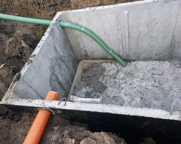 Szambo betonowe 10m3 cena z montażem. Instalacja wkopana w ziemię, widoczne rury doprowadzające.