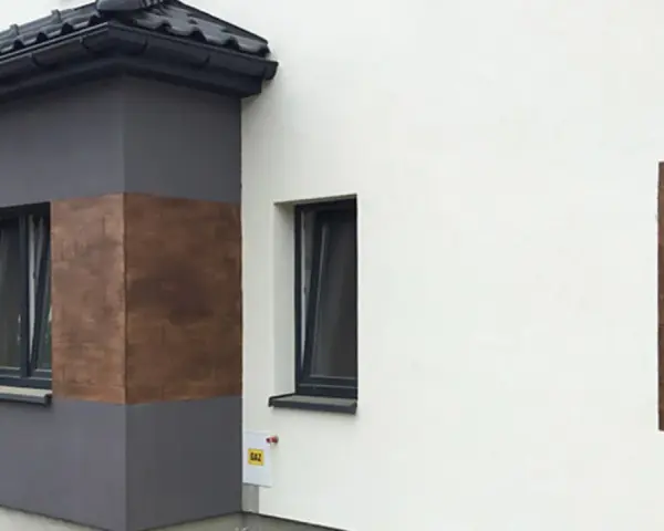 Nowoczesna elewacja z elementami imitującymi drewno, wykonana z tynków cementowo wapiennych.