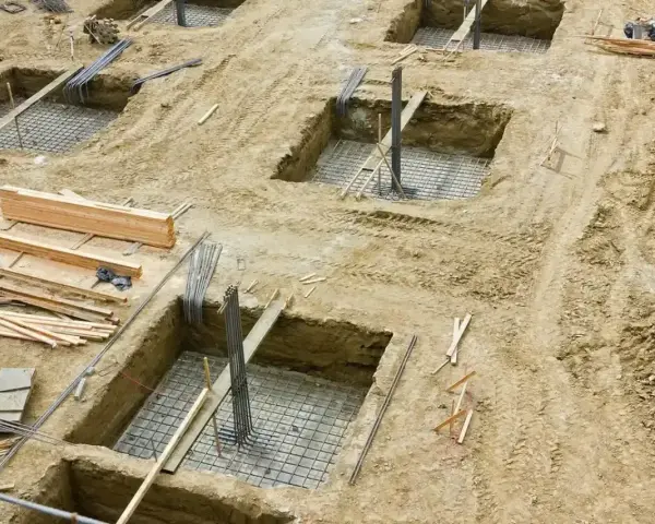 Wykopy pod fundamenty, zbrojenie i drewno budowlane. Trwa podbijanie fundamentów pod przyszły budynek.