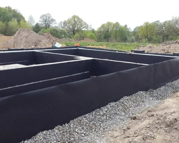 Fundament gotowy do izolacji. Czarna membrana z wypustkami, czyli izoplast b, chroni ściany przed wilgocią.