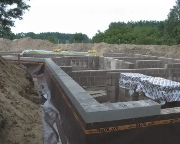 Fundament domu z bloczków betonowych, z widoczną izolacją i przygotowaniem pod keramzytobeton. Budowa w toku.