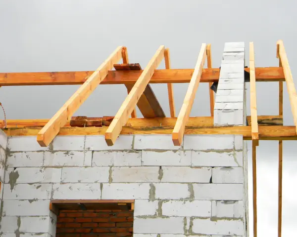 Drewniana więźba dachowa na budowie domu z bloczków betonowych. Sprawdź, jaka jest aktualna więźba dachowa cena.