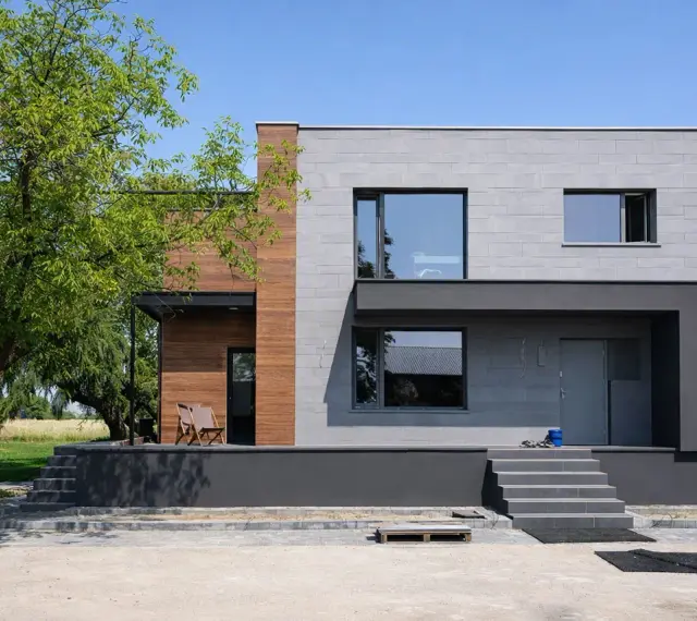 Nowoczesny dom z betonowych bloczków i drewna, nawiązujący stylem do **elewacji domów z lat 70-tych**, ale z odświeżonym, minimalistycznym charakterem.