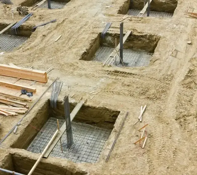 Wykopy pod fundamenty, zbrojenie i drewno budowlane. Trwa podbijanie fundamentów pod przyszły budynek.