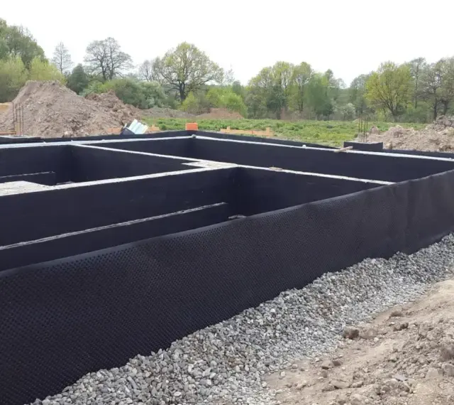 Fundament gotowy do izolacji. Czarna membrana z wypustkami, czyli izoplast b, chroni ściany przed wilgocią.