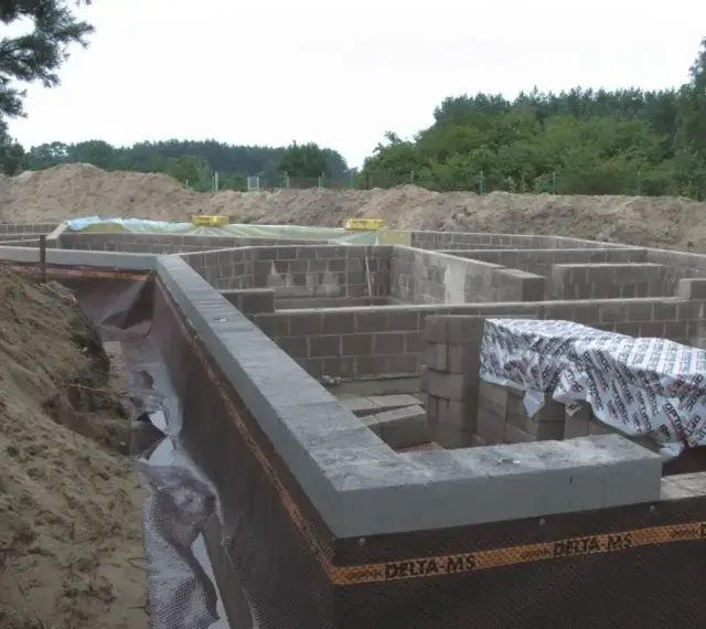 Fundament domu z bloczków betonowych, z widoczną izolacją i przygotowaniem pod keramzytobeton. Budowa w toku.