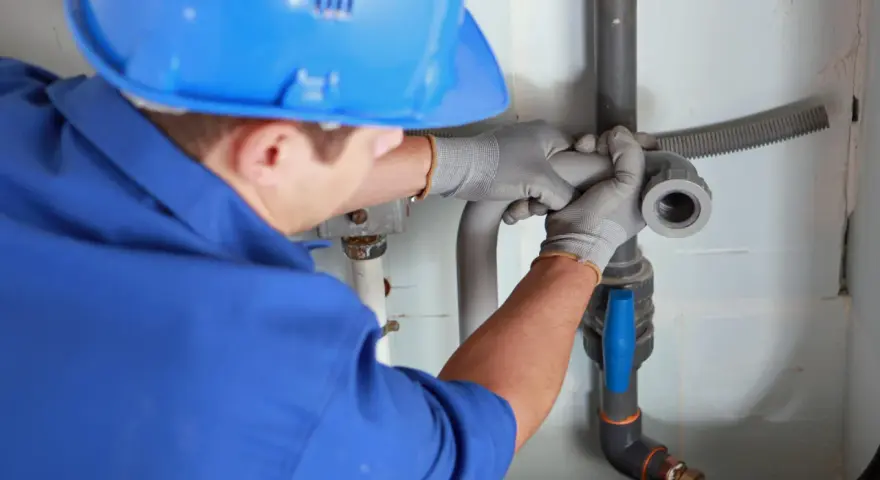 Instalator montuje odpowietrzenie kanału sanitarnego w domu parterowym.