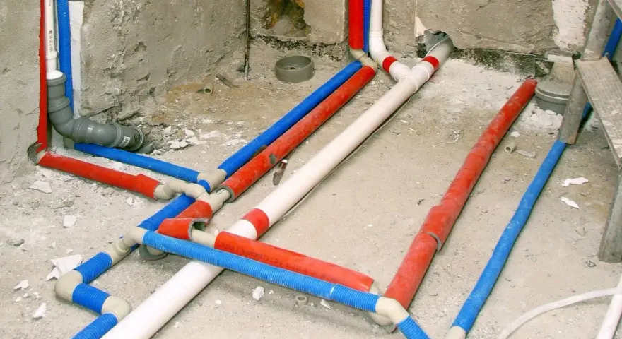 Skomplikowana instalacja wodna z rurami w kolorach czerwonym, niebieskim i białym, przygotowana do ukrycia pod tynkiem.