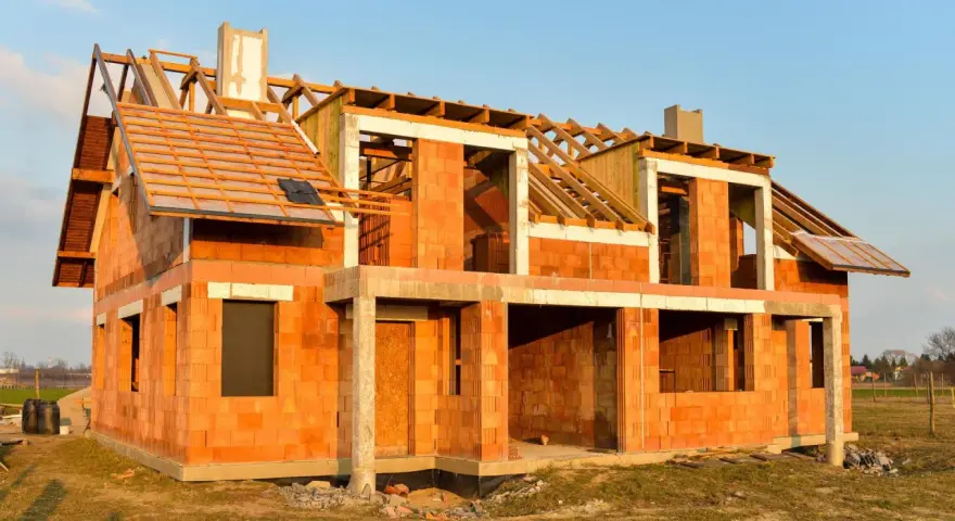 Budowa domu energooszczędnego z cegły ceramicznej. Widoczny szkielet dachu i otwory okienne.