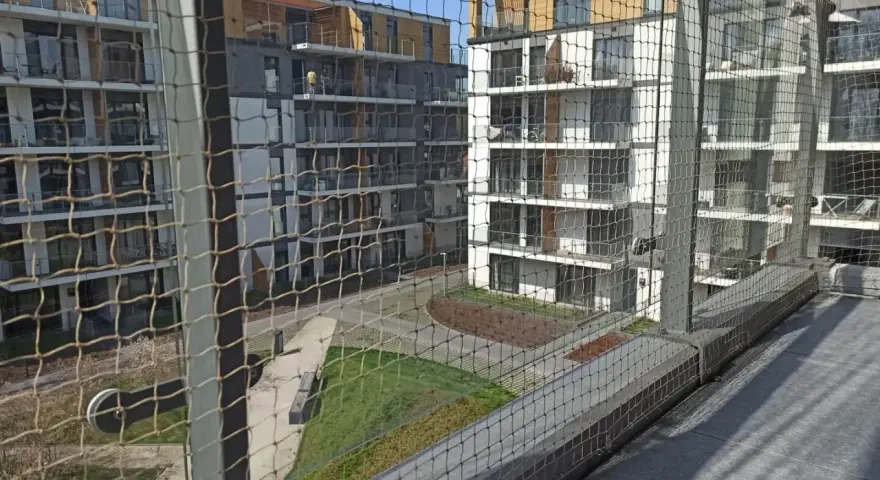 Nowoczesne bloki mieszkalne z balkonami, zabezpieczone siatką. Zastanawiasz się, ile kosztuje montaż siatki na balkonie?